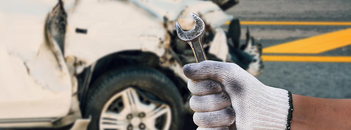 mechanic hand hold wrench with car crash accident damage background, auto body repair concept