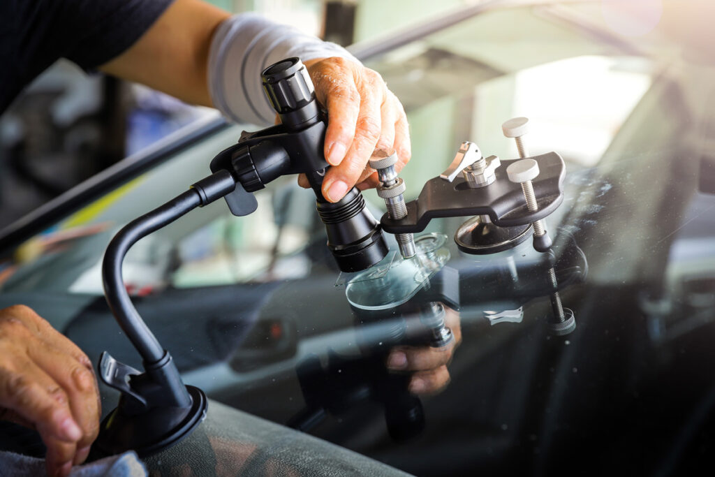 A person using a tool for auto glass repair on a windshield in El Paso.