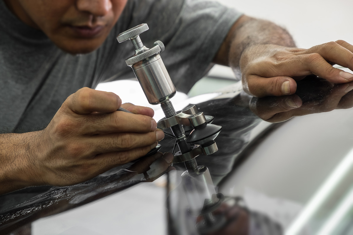 A professional performing auto glass repair on a car windshield in El Paso.