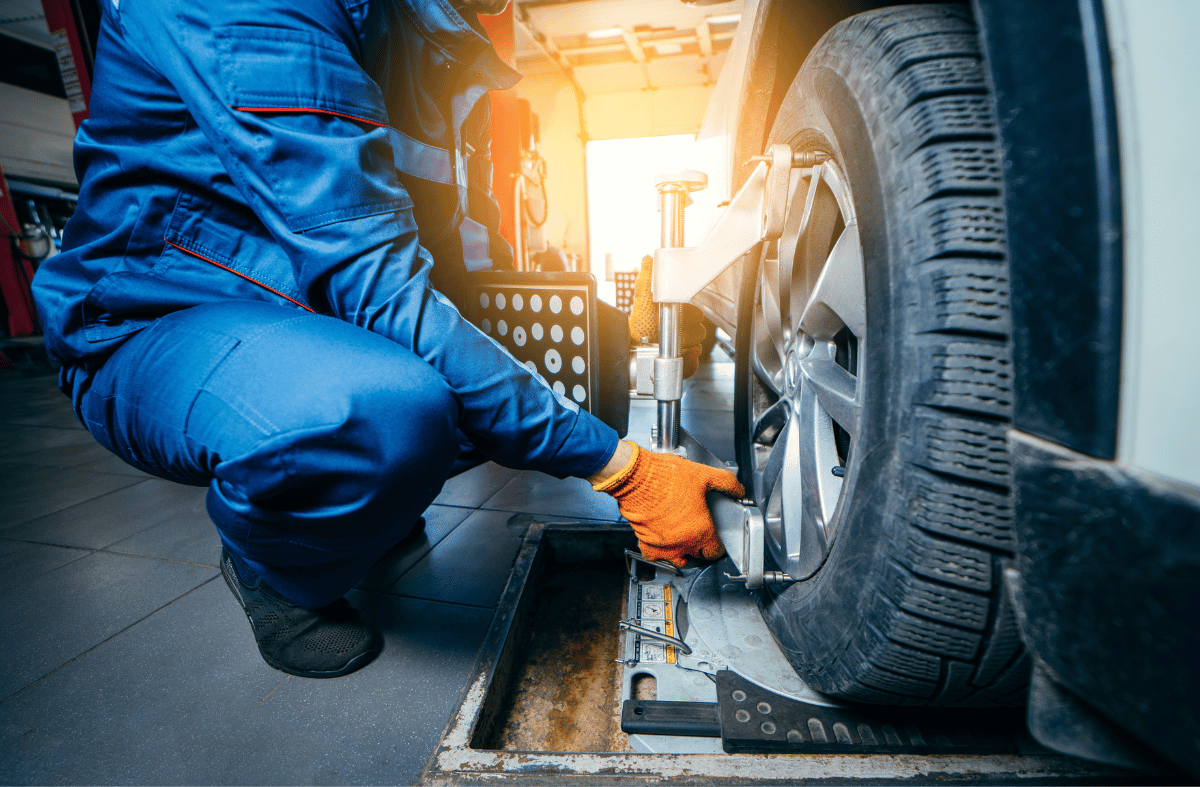 A mechanic performing wheel alignment service on a car
